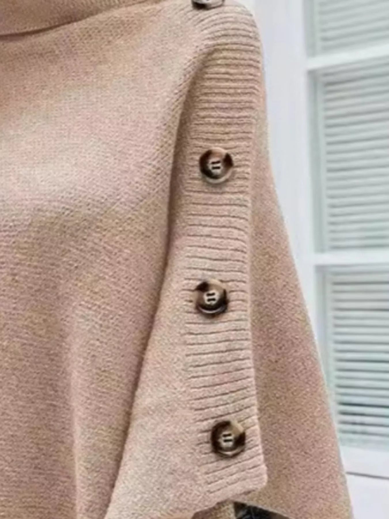 Close-up of a beige cardigan with button details on a blurred background