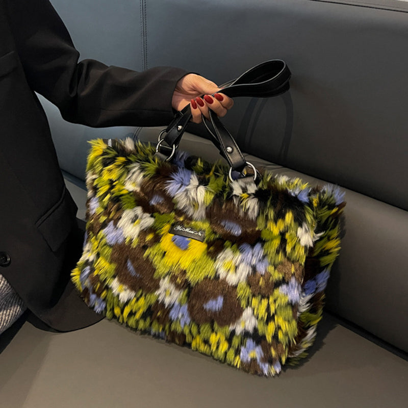 Floral-patterned handbag held by a person sitting on a car seat.