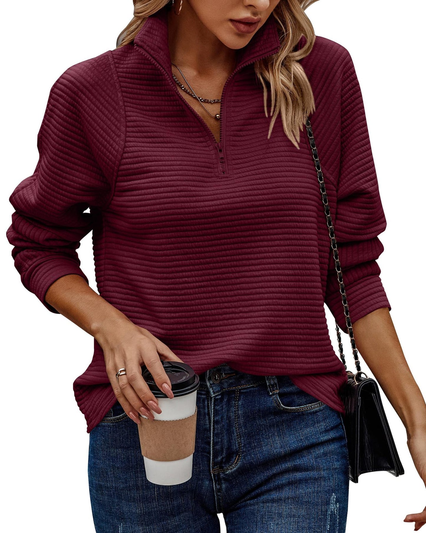 Woman wearing a maroon ribbed sweater holding a coffee cup.