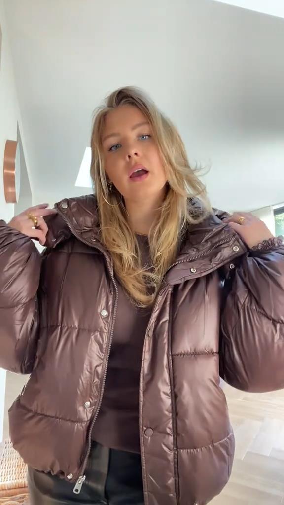 Person wearing a brown puffer jacket indoors