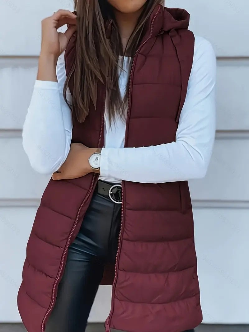 Person wearing a maroon puffer vest over a white long-sleeve shirt with a neutral background