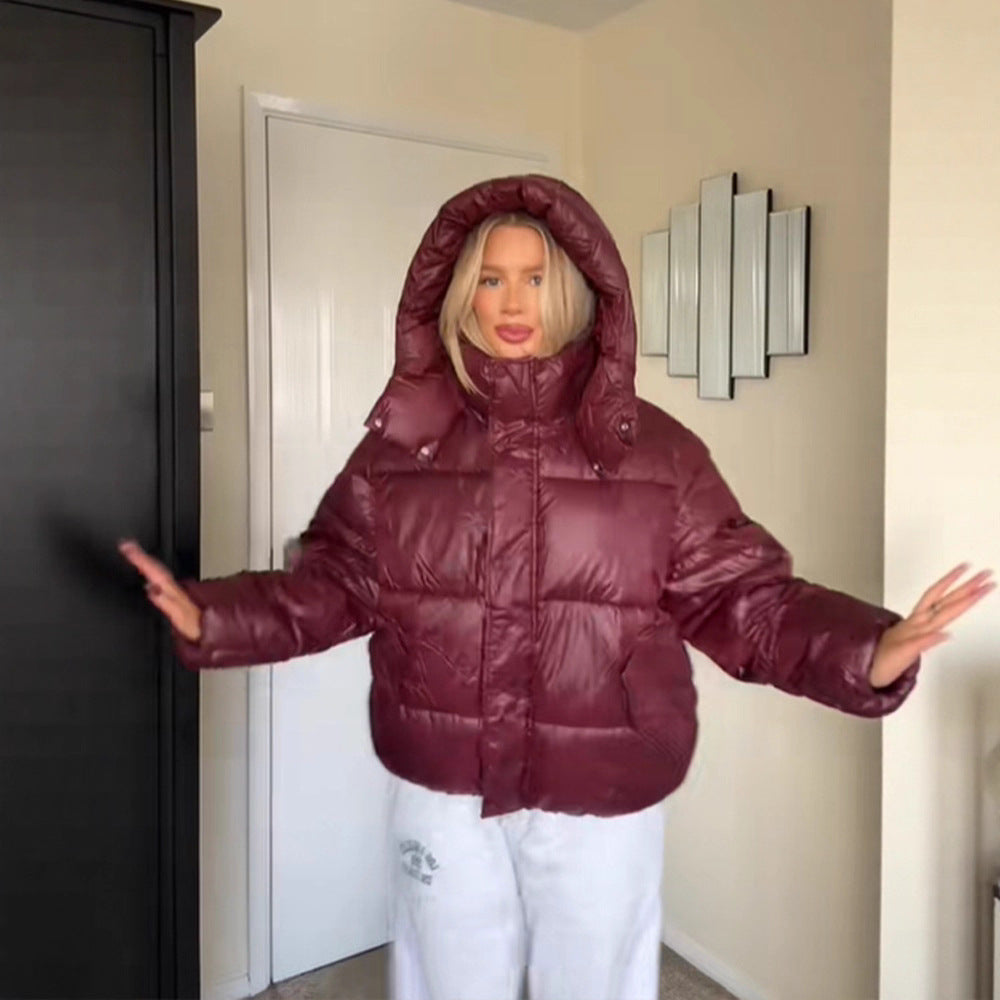 Person wearing a maroon puffer jacket in a room with a door and wall art.
