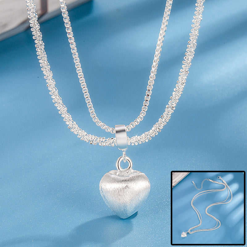 Silver heart-shaped pendant necklace on a blue background