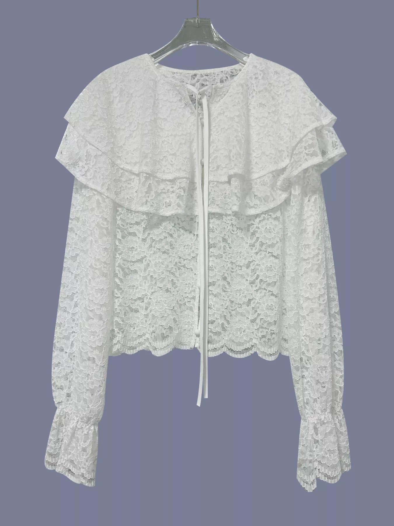 White lace top on a hanger against a dark background