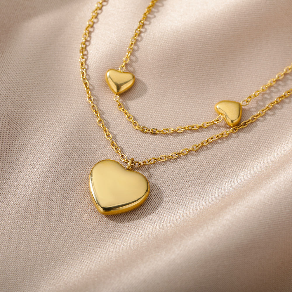 Gold heart-shaped necklace on a soft pink background