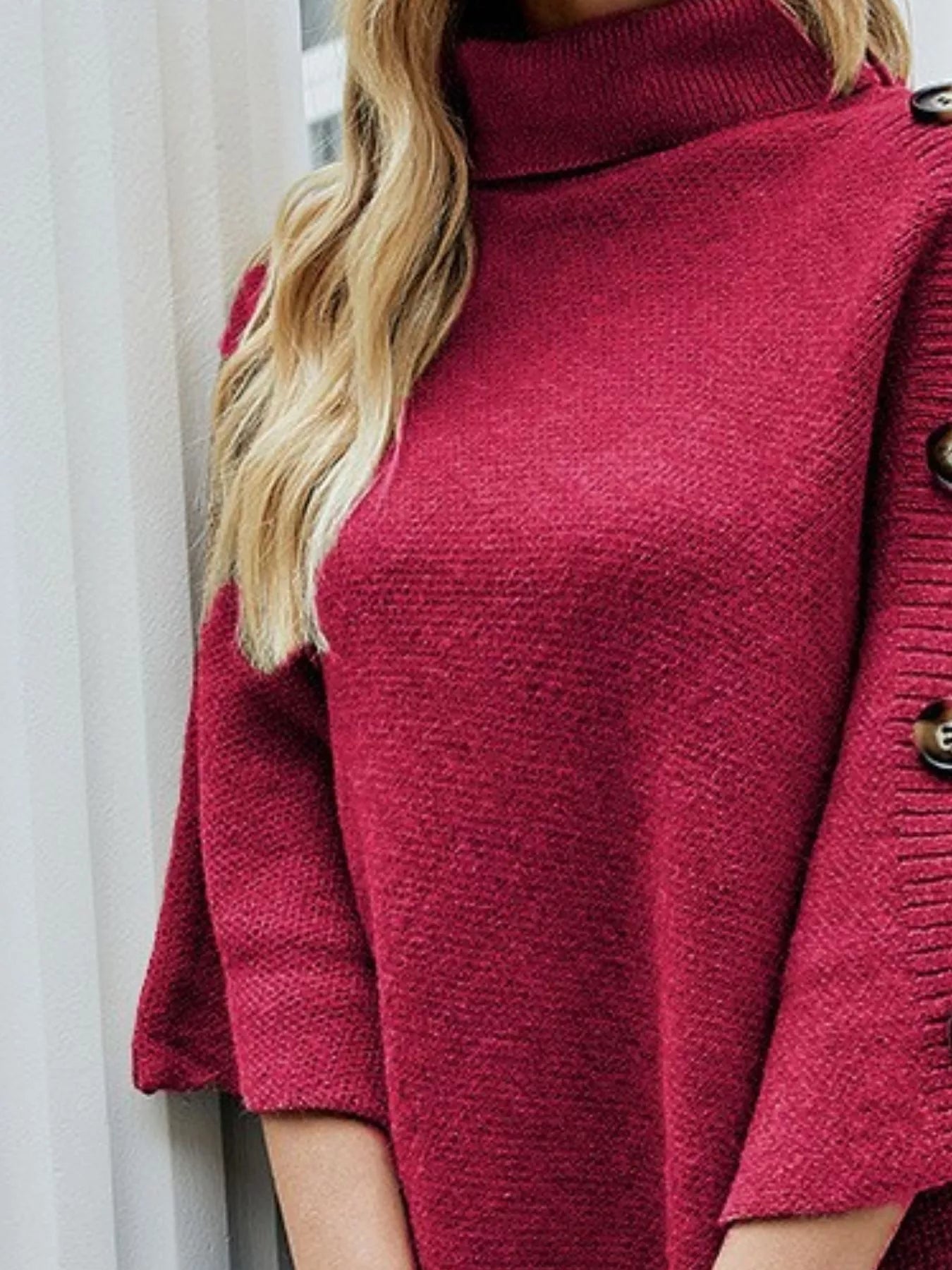 Close-up of a person wearing a red knitted sweater with buttons.