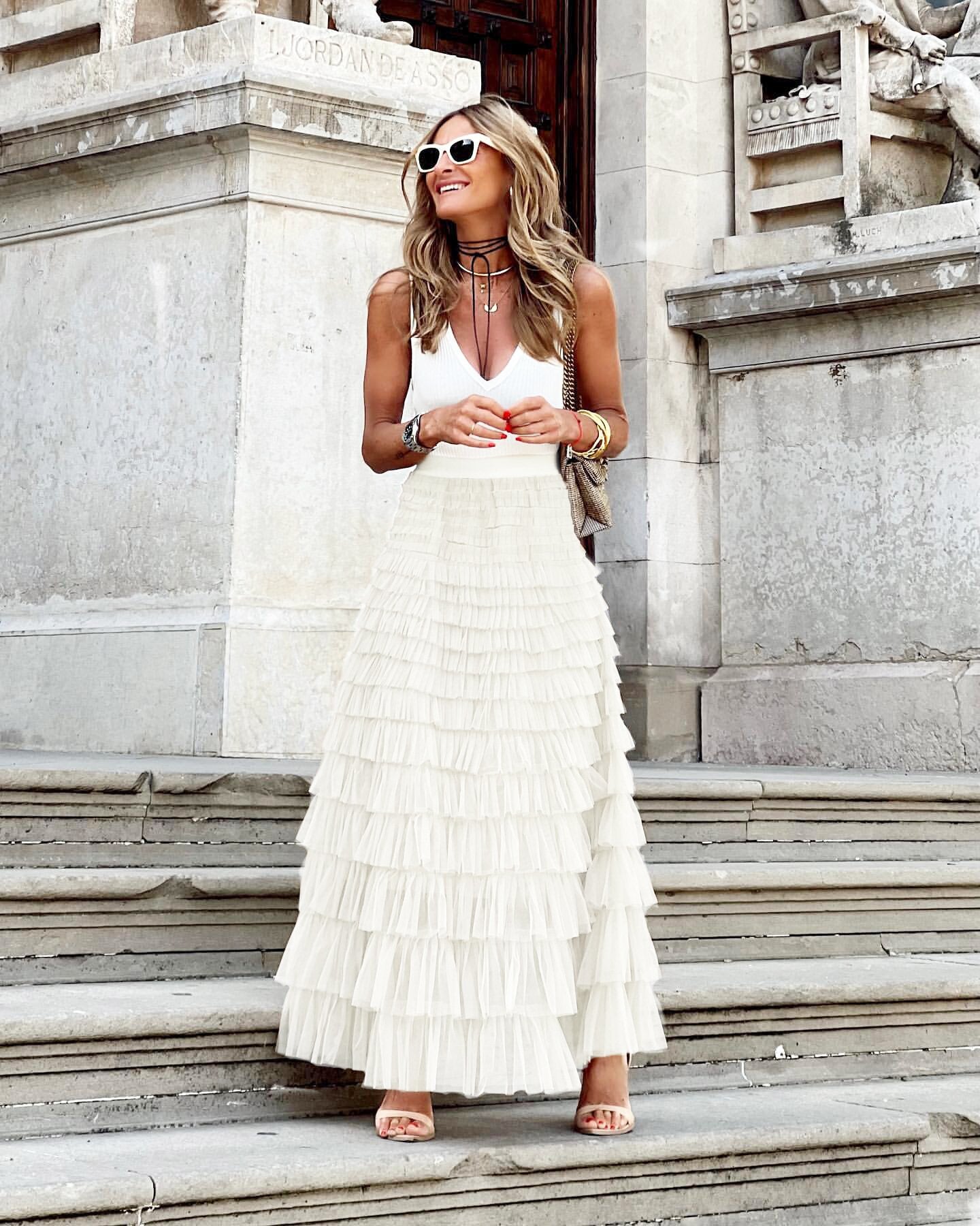Woman in a white dress standing on stone steps with classical architecture in the background