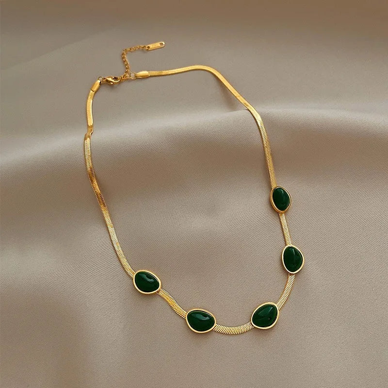 Gold necklace with green stones on a beige fabric background