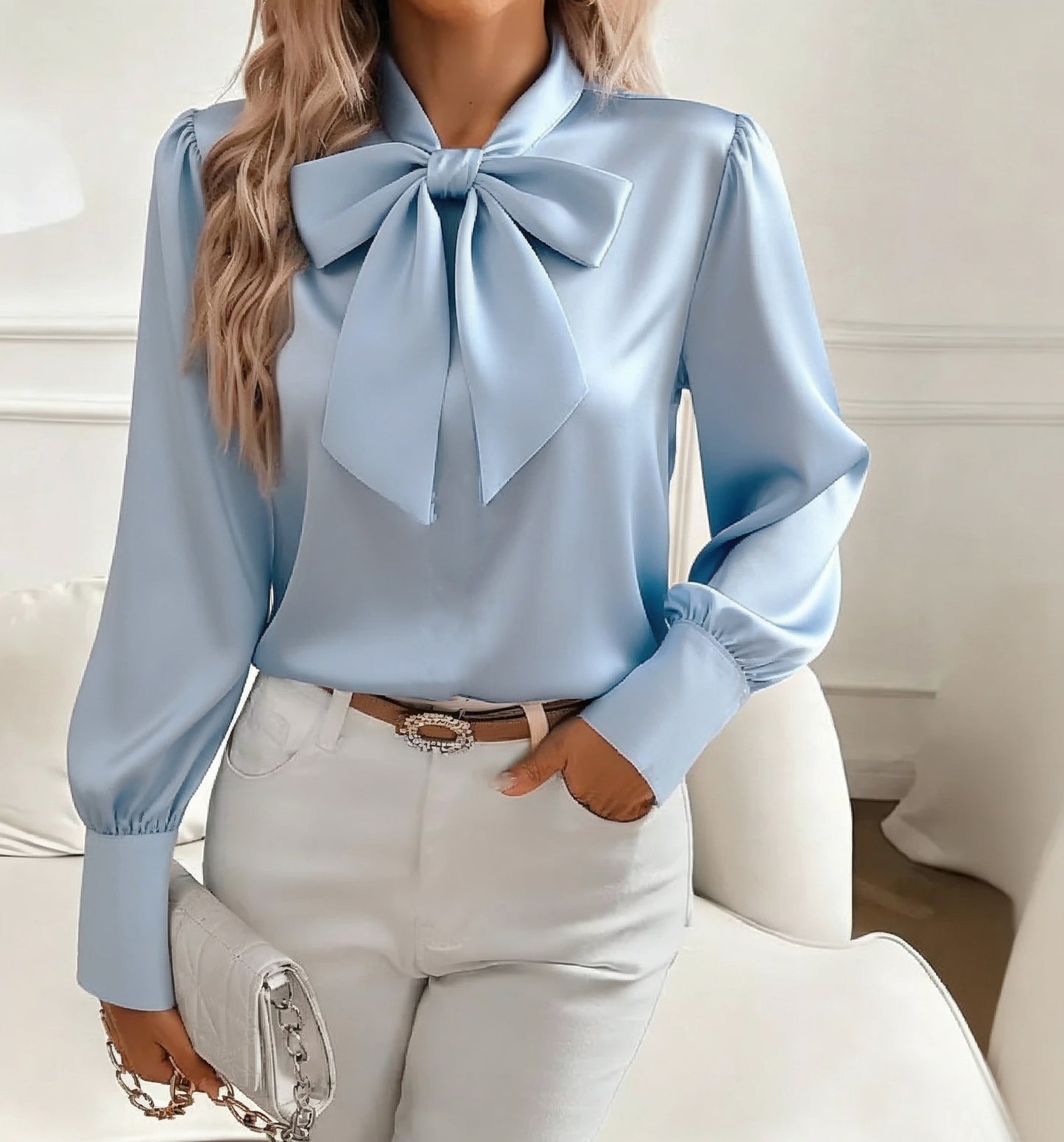 Light blue blouse with a large bow and white pants against a neutral background